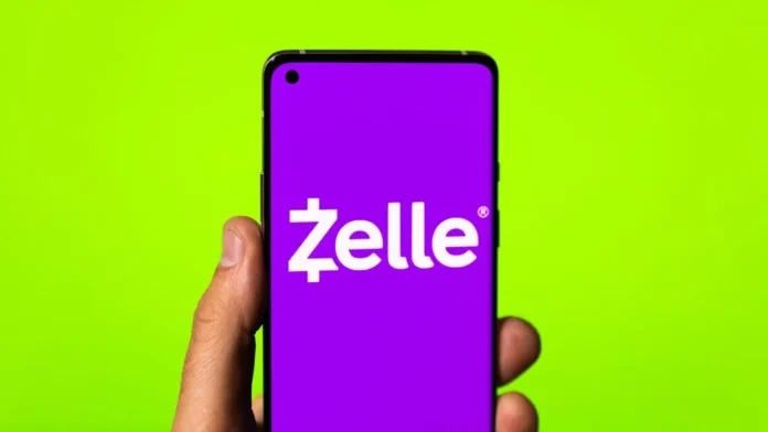 Hand holding a smartphone displaying the Zelle logo on a bright green background