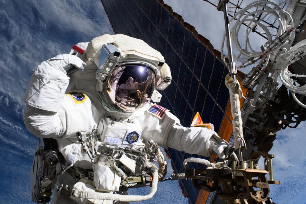NASA astronaut conducting a spacewalk outside the International Space Station with Earth in the background